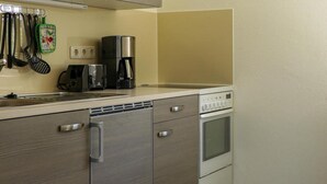 A compact kitchen with a microwave, coffee maker, and a clock on the wall. - Ferienwohnung Basteiblick in Pirna (Pirna)