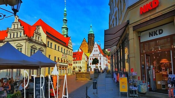 A cobblestone street with historic buildings, a clear blue sky, and a sign for 'NKD' on the right. - Ferienwohnung Basteiblick in Pirna (Pirna)