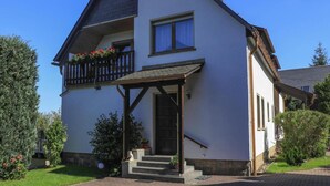 A two-story house with a balcony, a porch, and a small garden. - Ferienwohnung Basteiblick in Pirna (Pirna)