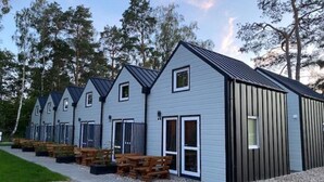 A row of cabins with a sloped roof, a gravel pathway, and wooden benches. - Bungalow in Dziwnow Near Baltic Sea (Dziwnów)