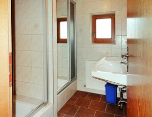 Un bagno con doccia, lavandino e finestra.