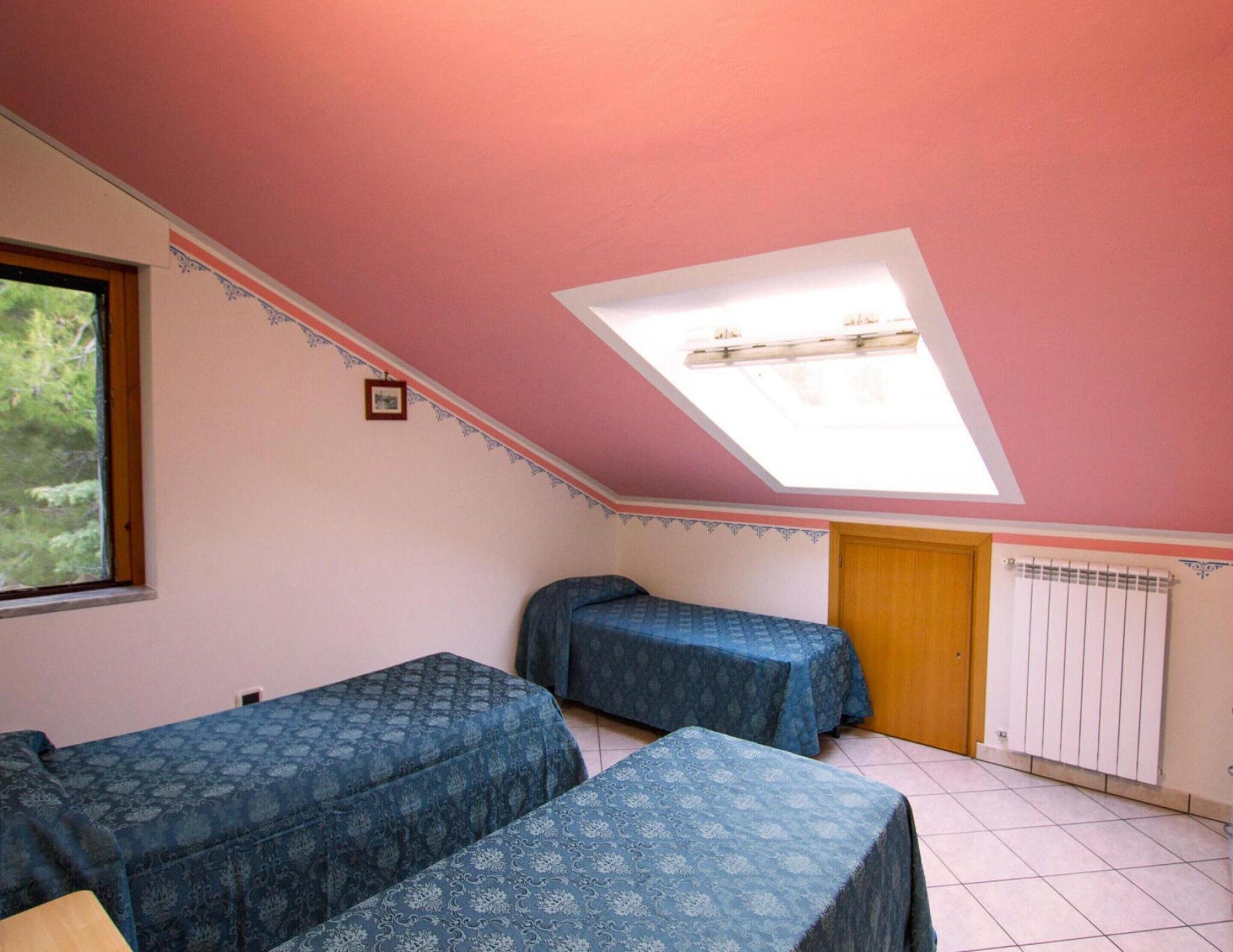 Una habitación con dos camas, un tragaluz, un radiador y una ventana.
