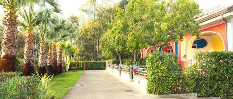 Un sendero bordeado de palmeras y un edificio con arcos coloridos.