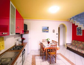 Une cuisine avec une table à manger et des chaises, un canapé et un escalier.