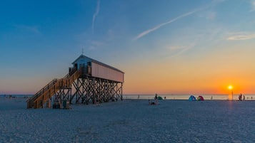 Una playa con un muelle de madera y una torre de salvavidas.