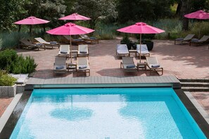 Un espace piscine équipé de chaises longues et de parasols.