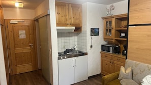 A compact kitchen with wooden cabinets, a microwave, and a sink. - Apartment in Wildschonau by Schatzberg Lift (Wildschönau)