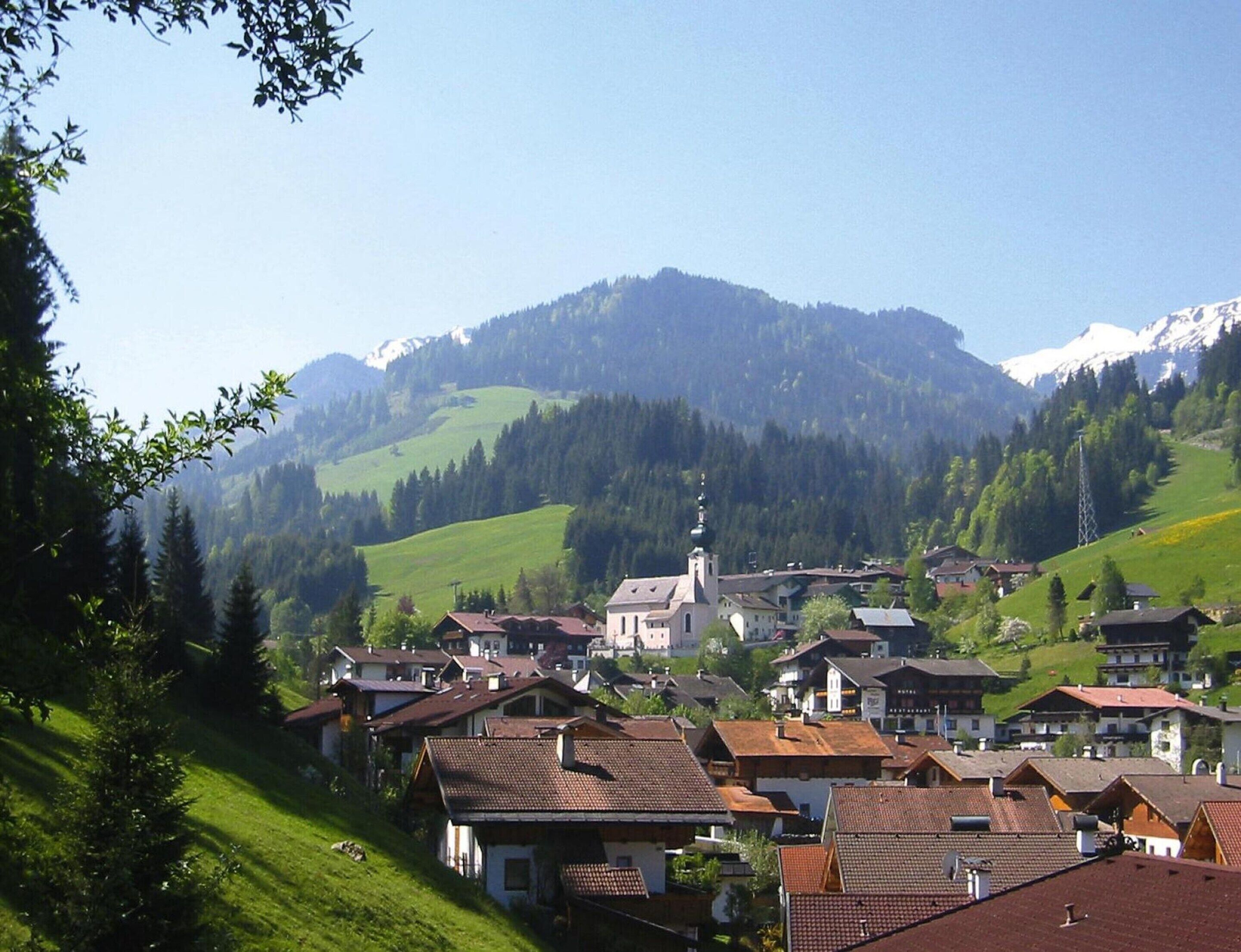 A village with traditional houses, a church, and a mountain backdrop.