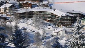 A snow-covered hotel with multiple buildings, including a prominent structure with a sign that reads 'Schlossberghaus.'