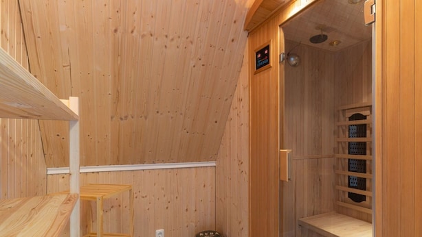 A wooden sauna room with a wooden bench, a sauna door, and a small shelf with bottles. - Ferienwohnung Kustenluft in Tating (Tating)