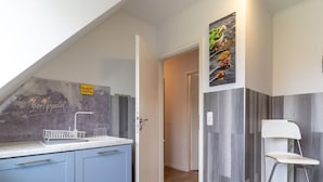 A modern kitchen with a built-in sink, blue cabinets, and a white chair. - Ferienwohnung Kustenluft in Tating (Tating)