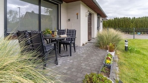 A patio with outdoor seating, a table with a bottle, and potted plants. - Ferienwohnung Kustenluft in Tating (Tating)