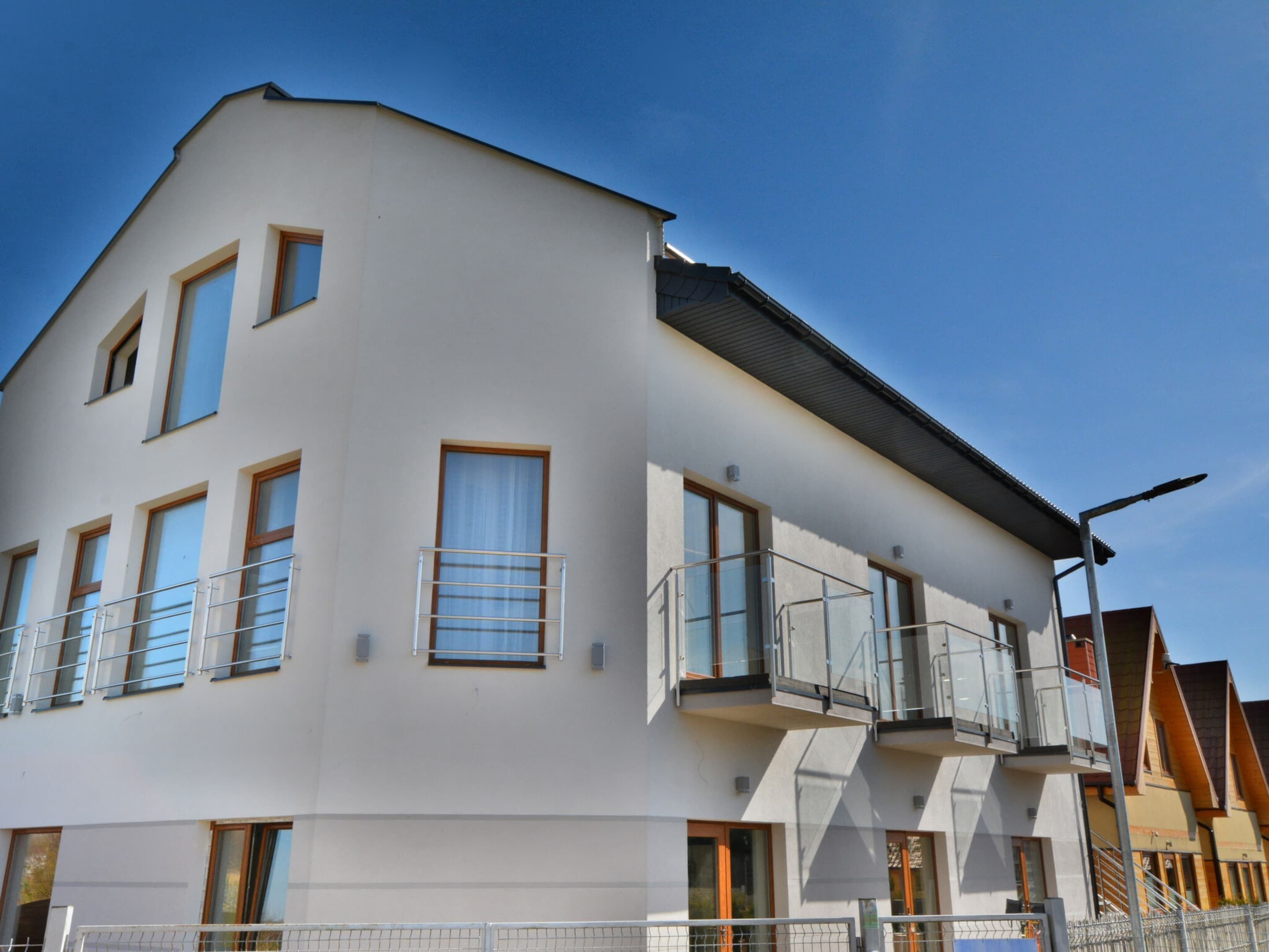 Un immeuble résidentiel moderne à plusieurs étages, doté de balcons, de grandes fenêtres et d’un toit plat.