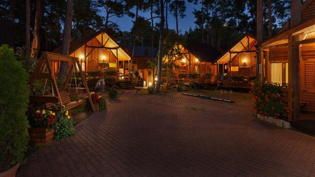 A wooden cabin-style lodging area with multiple cabins, paved pathways, and outdoor seating areas. - Holiday Homes Near the Seaside Beach, Pobierowo (Rewal)
