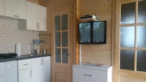 A kitchen with white cabinets, a wooden door, and a television mounted on the wall. - Holiday Homes With Terraces, Close to the Beach (Ustronie Morskie)