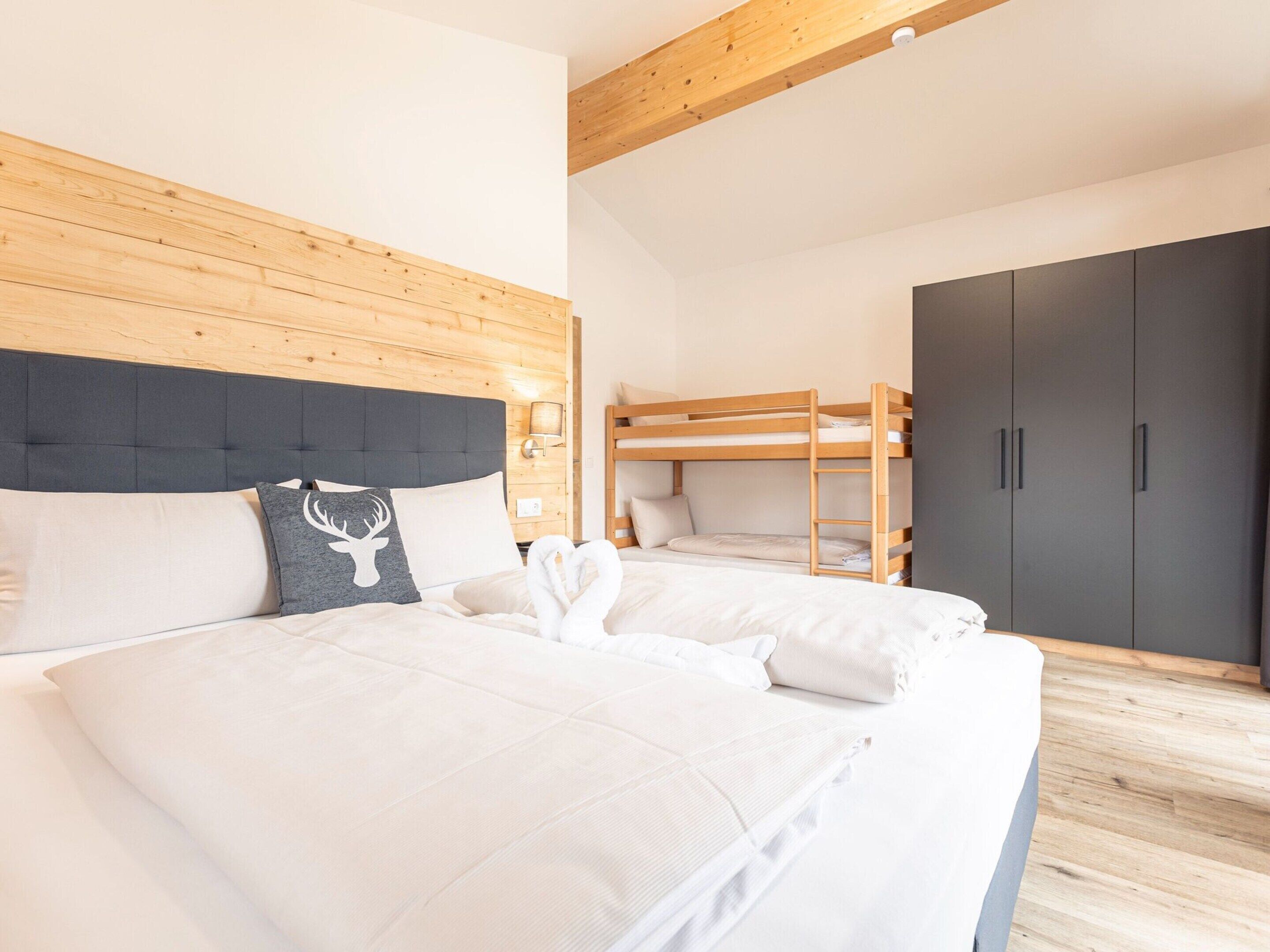Ein Schlafzimmer mit einem großen Bett, einem Holzkopfteil, einem Etagenbett und einem Kleiderschrank.