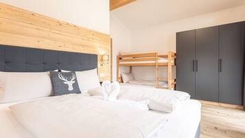 Ein Schlafzimmer mit einem großen Bett, einem Holzkopfteil, einem Etagenbett und einem Kleiderschrank.