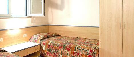 Un dormitorio con dos camas, un armario y una ventana.