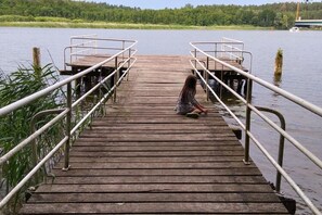 A wooden dock with metal railings leading to a small boat. - Ferienhaus in Petersdorf mit Schonem Garten (Fuenfseen)