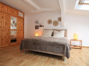 Ein Schlafzimmer mit einem Bett, einem Holzschrank, Wandbildern und einer Nachttischlampe.