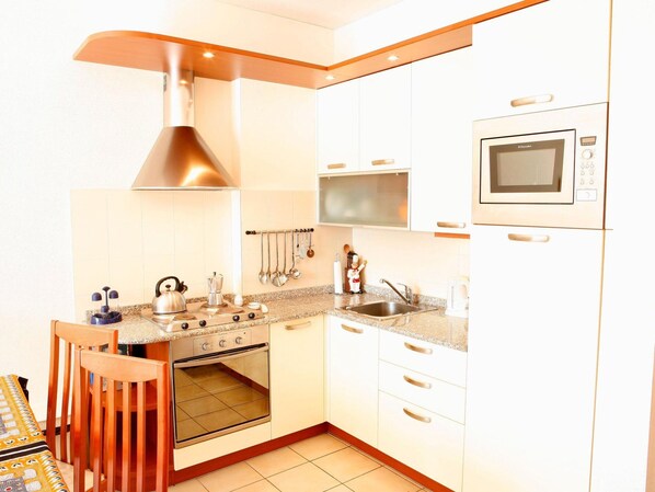 A compact kitchen with white cabinets, a built-in oven, a microwave, and a stove.
