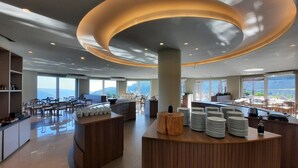 A modern hotel lobby with a central reception desk, seating areas, and large windows offering a view of the mountains. - Golden Gramado Resort (Gramado)