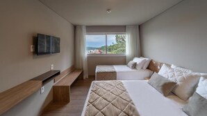 A hotel room with two beds, a TV mounted on the wall, a window with a view, and a bench. - Golden Gramado Resort (Gramado)