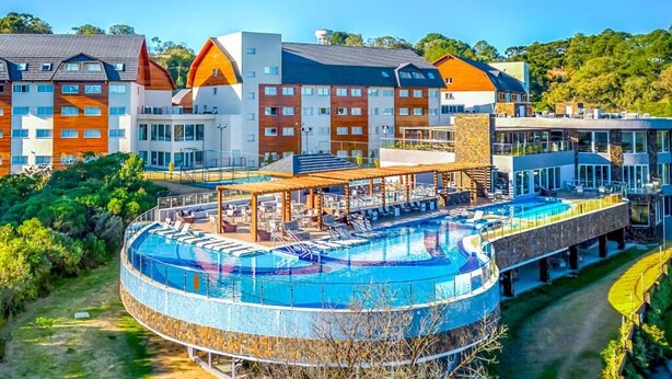 A modern hotel with a circular pool, multiple buildings with distinct architectural styles, and a well-maintained surrounding landscape. - Golden Gramado Resort (Gramado)