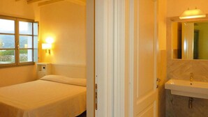 A bedroom with a bed, a bedside table, a nightstand, a window, and a bathroom with a sink and mirror. - Apartment in Elba With Panoramic Views (Rio)