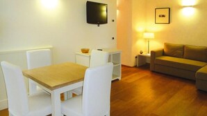 A living room with a wooden table, white chairs, a sofa, a TV, and a lamp. - Apartment in Elba With Panoramic Views (Rio)