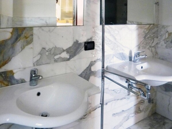 A bathroom with two white marble sinks and a glass partition. - Apartment in Elba With Panoramic Views (Rio)