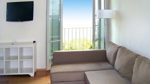 A living room with a beige sectional sofa, a white cabinet, and a television on the wall. - Apartment in Elba With Panoramic Views (Rio)