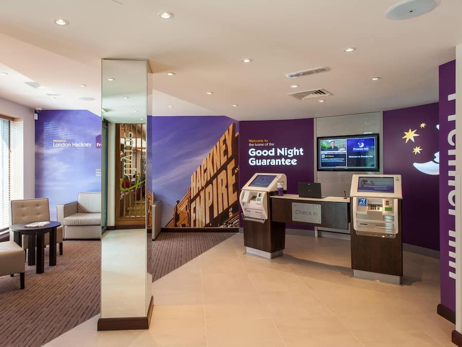 A hotel lobby with a check-in counter, seating area, and a large wall mural.