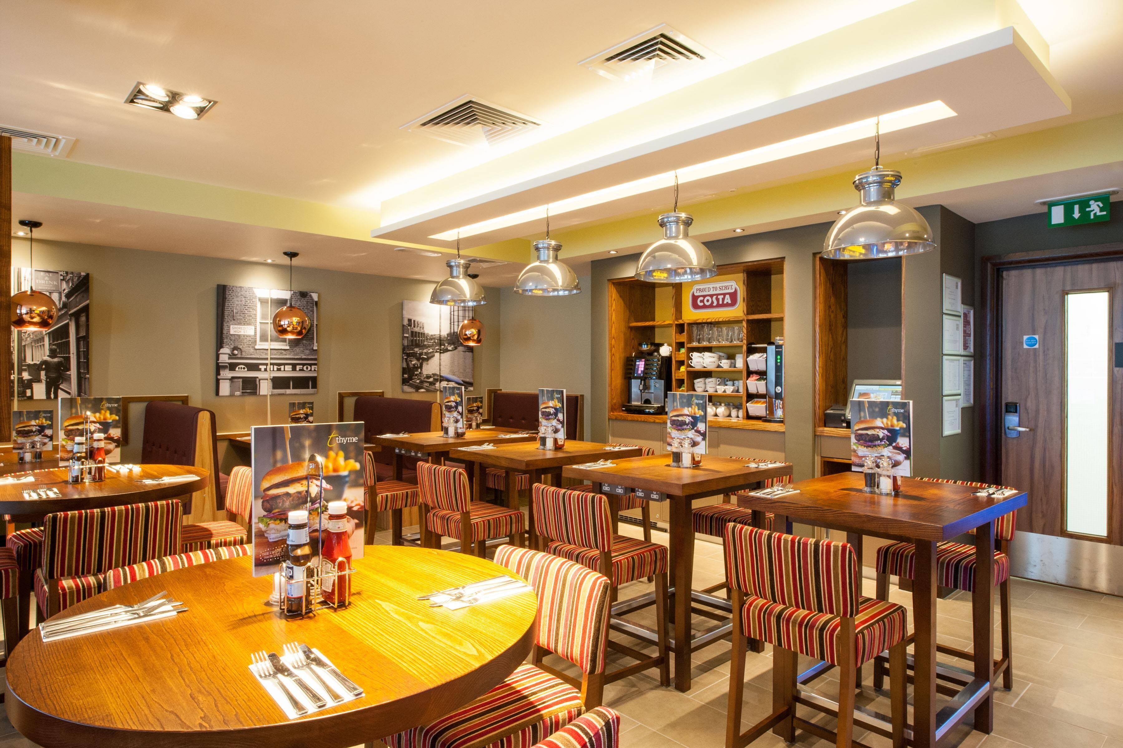 Un restaurante con varias mesas y sillas, una barra con menú y luminarias colgantes.