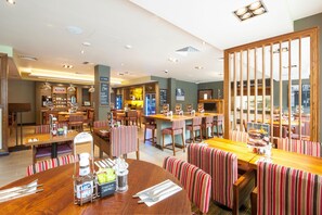 A restaurant with booths and tables, a bar area, and a display of various items. - Premier Inn London Hackney (London)