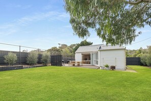 A backyard with a small shed, a wooden table and chairs, and a well-maintained lawn. - Back Beach Portsea: 4  BR, 2.5  BA House in Portsea, Sleeps 7 (Portsea)
