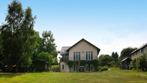 A two-story house with a large front lawn, a balcony, and a small shed in the background. - Ferienwohnung, Zemitz (Zemitz)