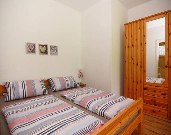 A bedroom with two single beds, a wooden wardrobe, and three heart-shaped wall decorations. - Ferienwohnung, Zemitz (Zemitz)