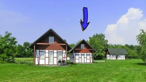 A row of traditional wooden houses with a large open grassy field in front. - Ferienhaus am Partwitzer See, Elsterheide (Elsterheide)