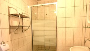 Een badkamer met een douchecabine van glas, een wastafel en een handdoekdispenser.