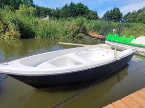 Een kleine, smalle boot afgemeerd bij een houten steiger.
