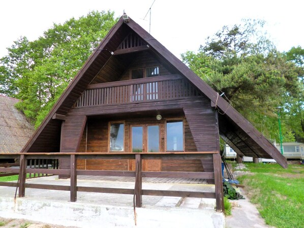 Een houten chalet met een schuin dak, een balkon en een veranda.