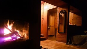 Una habitación acogedora con chimenea, paredes de madera y un espejo.
