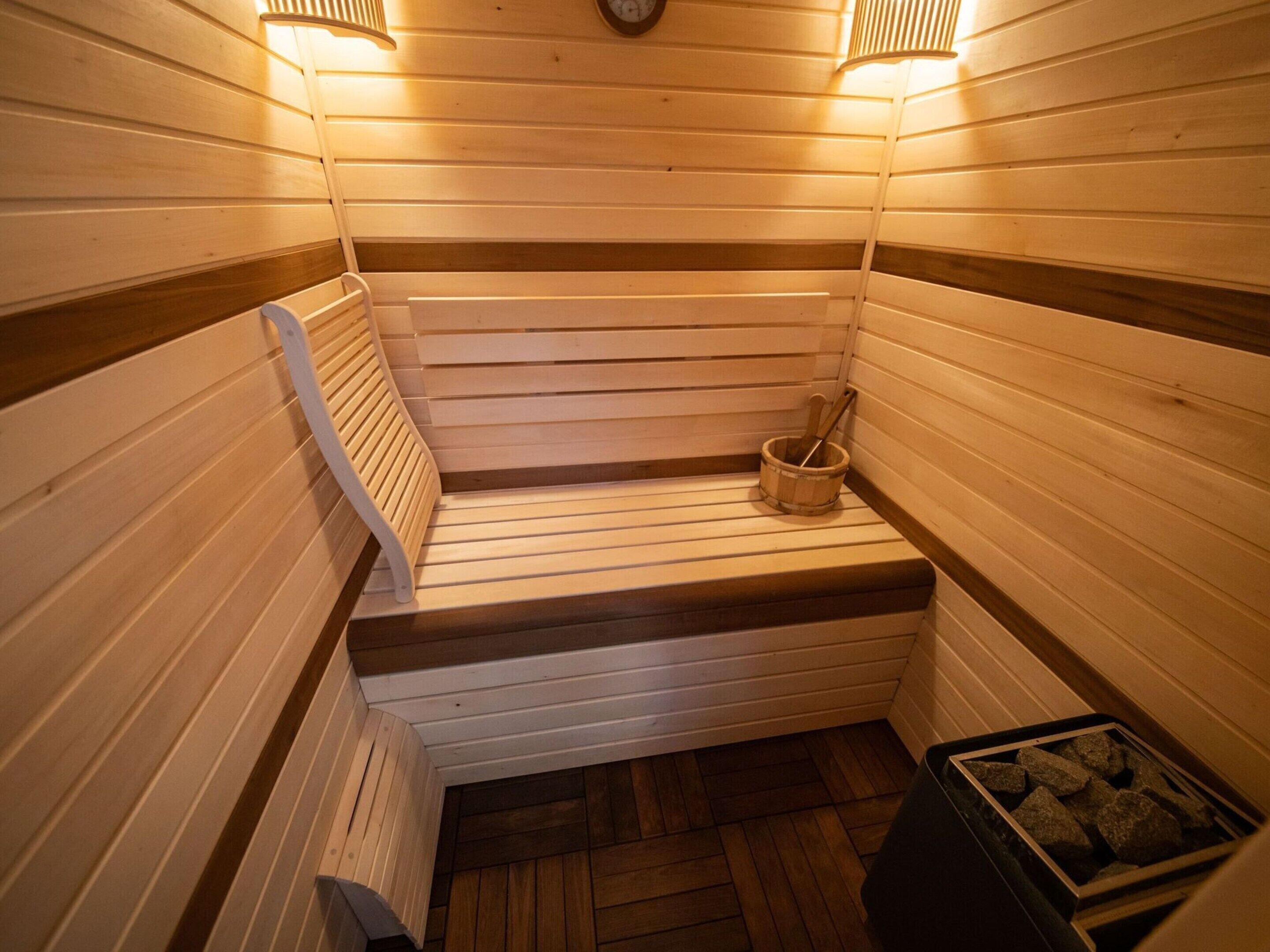 A sauna with wooden benches and a bucket.