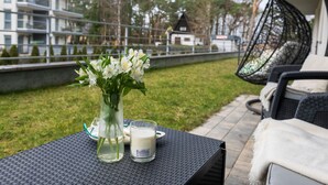 A patio with a table set for two, featuring a vase of white flowers and a candle. - Holiday Apartment Right on the Beach, Pobierowo (Rewal)