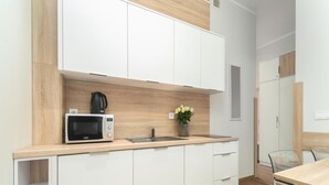 A modern kitchen with white cabinets, a microwave, a sink, and a vase with flowers. - Comfortable Holiday Apartment by the Beach (Rewal)