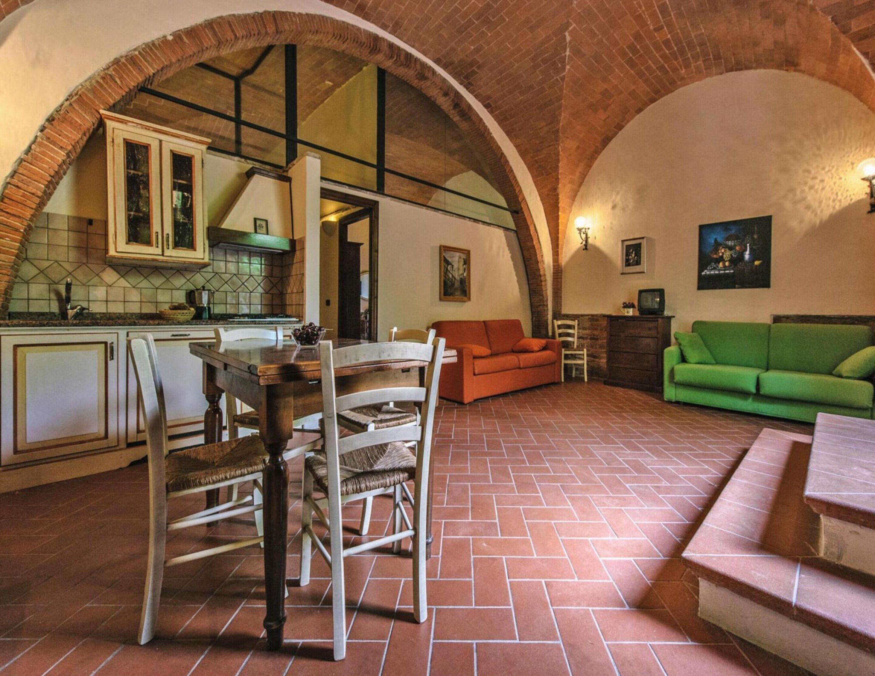 A spacious living area with a dining table, chairs, a sofa, and a green couch.