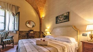 A room with a bed, a chair, a mirror, a wall-mounted painting, and a lamp. - Apartment in Santo Pietro Belvedere With Pool-formerly TUI Ferienhaus (Capannoli)
