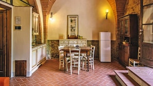 A rustic kitchen with a brick arch, a dining table with chairs, a refrigerator, and cabinets. - Apartment in Santo Pietro Belvedere With Pool-formerly TUI Ferienhaus (Capannoli)