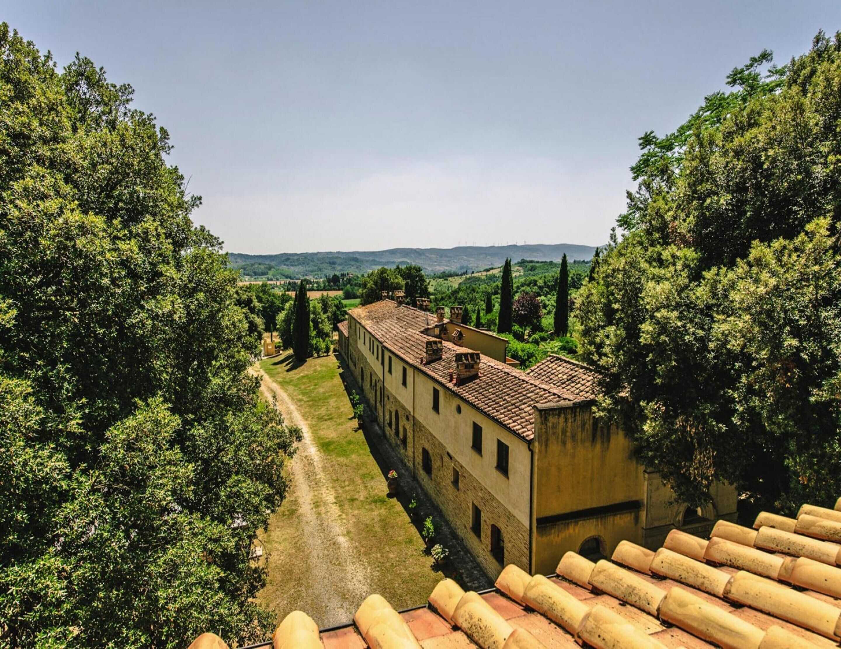 Ein Gebäude mit Ziegeldach, umgeben von Bäumen und blauem Himmel.
